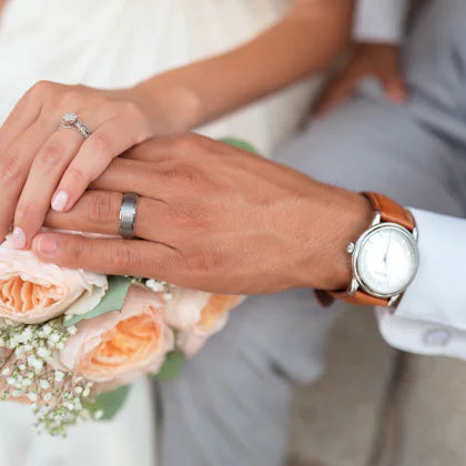 Two hands with wedding rings above a bouquet