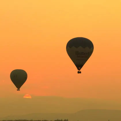 Two hot-air balloons against an orange sky