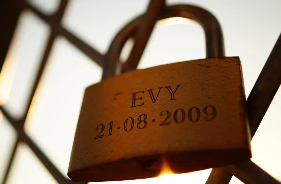 A brass padlock engraved with a name and a date, in warm backlight.